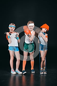 Three active kids in sportswear posing with sport equipment