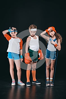 Three active kids in sportswear posing with sport equipment