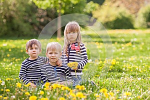 Three adorable kids, dressed in striped shirts, hugging and smiling