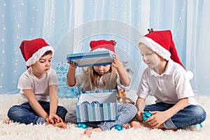 Three adorable kids, preschool children, siblings, having fun for Christmas, opening box with decoration