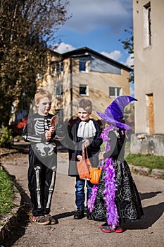 Three adorable trick or treaters begging for Halloween candy