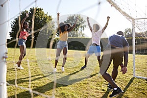 Three adults celebrate scoring goal against their friend