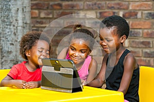 Three african kids playing together on tablet.