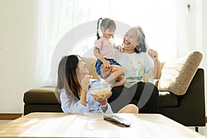 Three age ranges, Asian niece and grandma enjoying watching movies