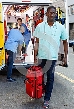 Three ambulance doctors posing in ambulance car with medical equipment