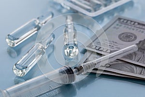 Three ampullas, expendable syringe for vaccination and paper money. The concept of insurance medicine, high cost of