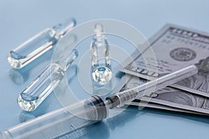 Three ampullas, expendable syringe for vaccination and paper money. The concept of insurance medicine, high cost of drugs