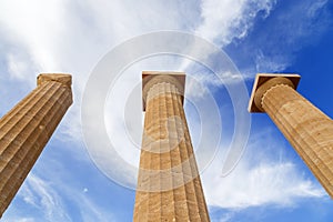 Three ancient greek pillars against blue sky