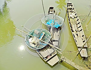 Three ancient wooden boats in the canal with fishing tools.