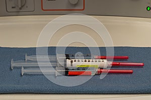 Three anesthesia drugs syringes with an anesthesia machine in the background.