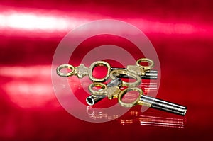 Three Antique Brass Pocket Watch Keys Laying on Red Surface