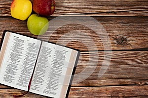 Three apples in different colors with Holy Bible Book isolated on wooden table