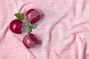 Three apples with green leaves on fur pink towel copy space