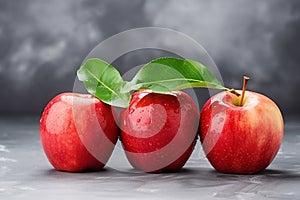 Three apples with leaves on table, dark background