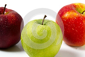 Three apples with water drops. Delicious appetizing beautiful fresh green and red apples on a white background.