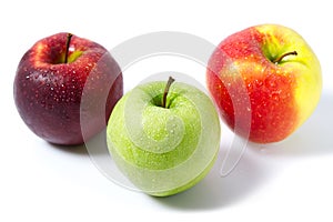 Three apples with water drops. Delicious appetizing beautiful fresh green and red apples on a white background.