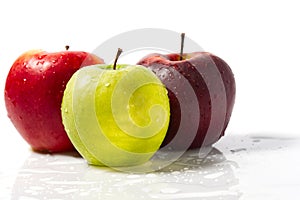 Three apples with water drops. Delicious appetizing beautiful fresh green and red apples on a white background.