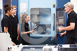 Three Apprentices Working With Engineer On CNC Machinery