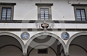 Three arcades, three windows with two circles containing colored terracotta sculptures and a bust of the historical building, whic