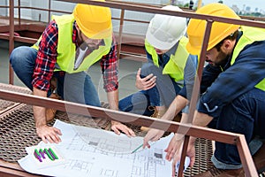 three architects in hardhats working with blueprints