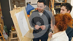 Three art students standing next to the easel and having a discussion photo