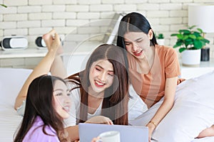 Three Asian cheerful happy female girlfriends in casual outfits sitting resting relaxing reading novels book browsing surfing