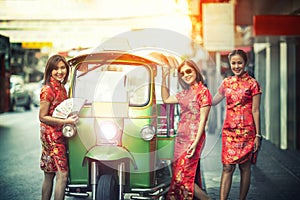 Three asian woman wearing chinese traditon clothes standing beside tuktuk in yaowaratch road chinatown bangkok thailand