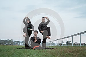Three Asians wearing pencak silat uniforms with formations photo