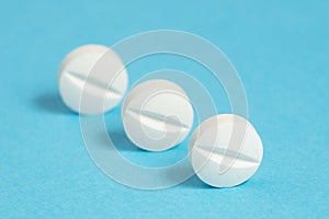 Three aspirin tablets on a blue background