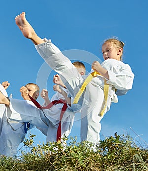 Three athletes in karategi are beating punch mae geri