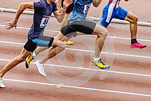 three athletes runners running synchronously together sprint race in track