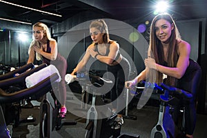Three attractive athletic girls exercising together on cycling class at gym