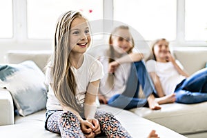 Three attractive child girls in casual clothes watching TV at home