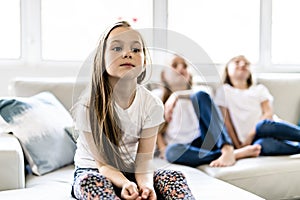 Three attractive child girls in casual clothes watching TV at home