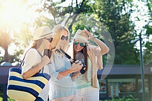 Three attractive girls looking at photos on their camera at summer holidays