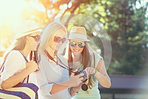 Three attractive girls looking at photos on their camera at summer holidays