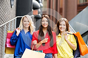 Three attractive happy female friends walking in the city center with shopping bags