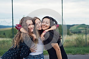 Three attractive teenage girls outdoors on playground.