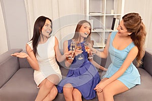 Three attractive young girlfriends celebrating with champagne and clinking