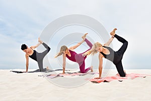 Three attractive young women perform yoga exercises