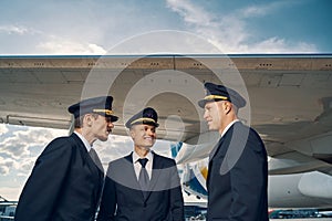 Three aviators having a conversation by a landed jetliner