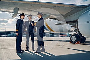 Three aviators having a conversation by a landed plane