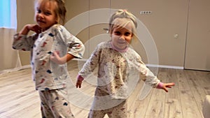 Three baby girls triplets sister are dancing at home in the room, pajamas are dressed