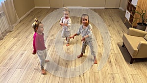 Three baby girls triplets sister are dancing at home in the room, pajamas are dressed