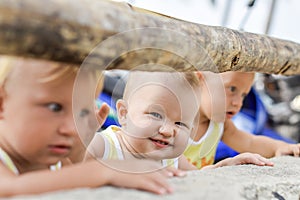 Three baby Toddler looking through fence on the hens and roosters in the henhouse. The yellow shirts.