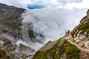 Three backpackers standing mountain trail looking at beautiful view