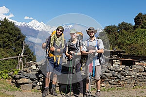 Three backpackers tourists posing, snow mountains peaks ridge.