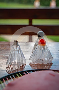 Three Badminton shuttles or birdies on a table outside with a racket, Blurry background
