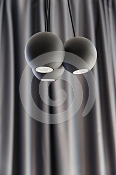 Three ball shaped LED illuminators are hanging from the ceiling. Black curtain on the backround photo