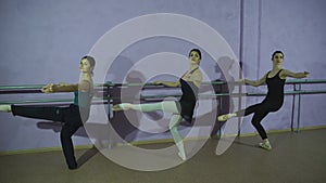 Three ballerinas Practicing At Ballet Barre In Dance Studio